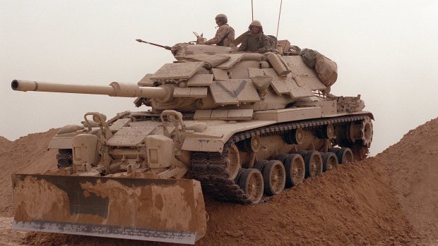 A tank negotiates a sand berm during an operation in the Gulf War.