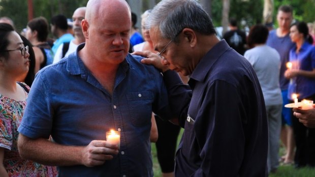 New Hope Community Church pastor Robert Chua comforts a well-wisher at a candelight vigil for Queenie.
