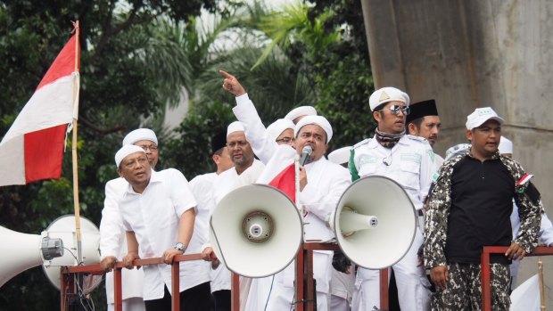 Indonesian police have denied that they are afraid to take on Habib Rizieq, seen here flanked by his supporters at Monday's rally outside police headquarters.