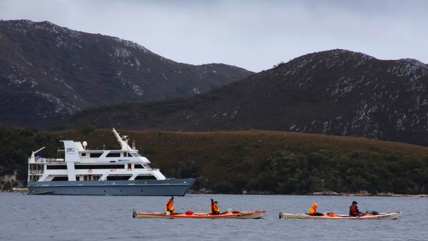 Guests take to Bathurst Harbour in kayaks with the cruise ship Coral Expedition I in the background.