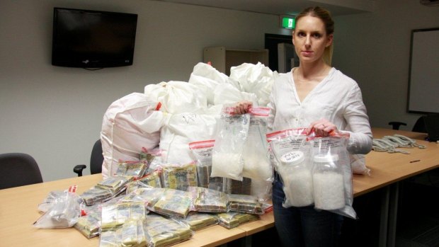 A police officer with the cash and drug haul. 