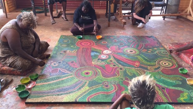 Women at Tjala Arts, in Amata community, painting the Honey Ant Dreaming.
