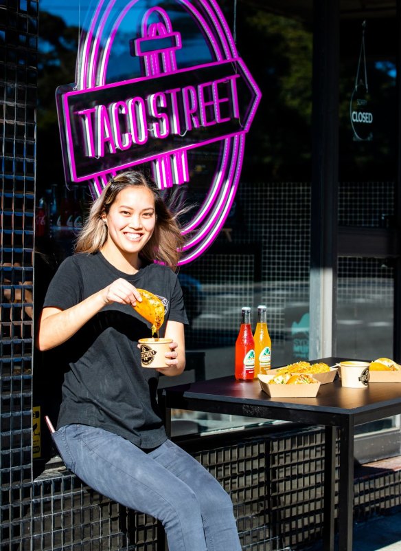 Taco Street manager Annabelle Luu dips a birria filled tortilla in consomme.