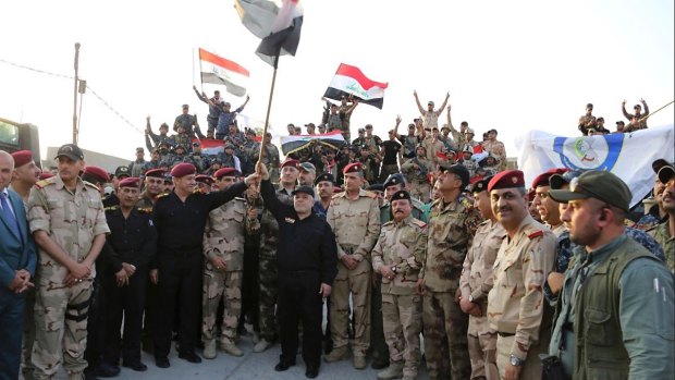 Iraq's prime minister Haider al-Abadi raises the national flag as he addresses forces  on the edge of Mosul's Old City.