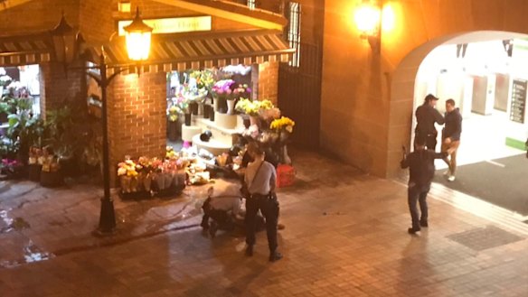 Police stand over a man at Central Station in Sydney following the shooting.