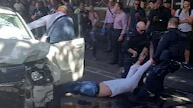 Police drag a man from the scene of the Melbourne CBD Flinders Street crash in December.