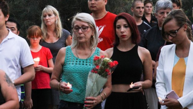 Residents and well-wishers pay their respects at a candelight vigil.