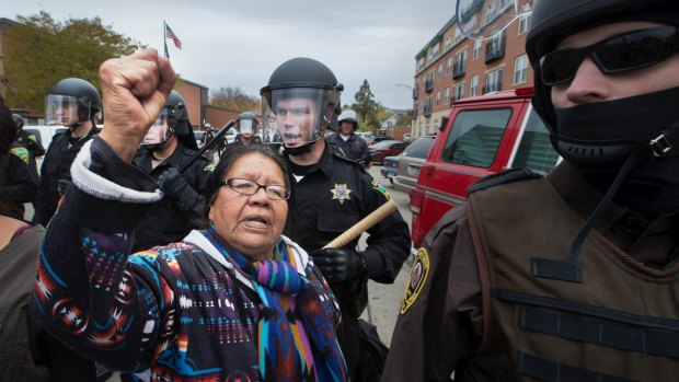 Faenette Black Bear, 63, Lakota, raises her fist in defiance as riot police push peaceful protesters away from the Morton County Court House. 