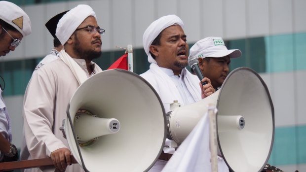 Rizieq Shihab (with microphone) speaks at a protest in January. He has now been named as a suspect by police.