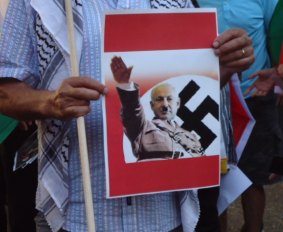 Outside Sydney's Town Hall, a protester holds a depiction of Israeli Prime Minister Benjamin Netanyahu as Adolf Hitler.