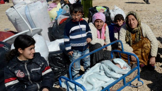 Kurds wait at the Mursitpinar border crossing on Monday as they prepare to return to Kobane.