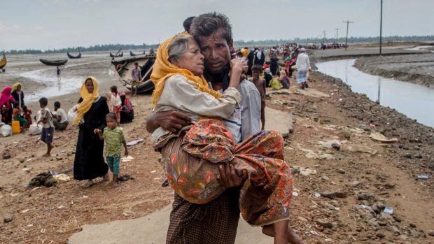 A Rohingya Muslim man Abdul Kareem walks towards a refugee camp carrying his mother Alima Khatoon after crossing over from Myanmar into Bangladesh.