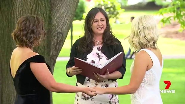 Celebrant Maria Aguilera (centre) officiates at the wedding of Amy and Elise McDonald in Carlton Gardens.