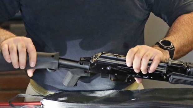 Clark Aposhian, chairman of the Utah Shooting Sports Council, attaches a little-known device called a "bump stock" to a semi-automatic rifle at the Gun Vault store and shooting range.