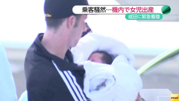 The father carries his newborn daughter off the plane.