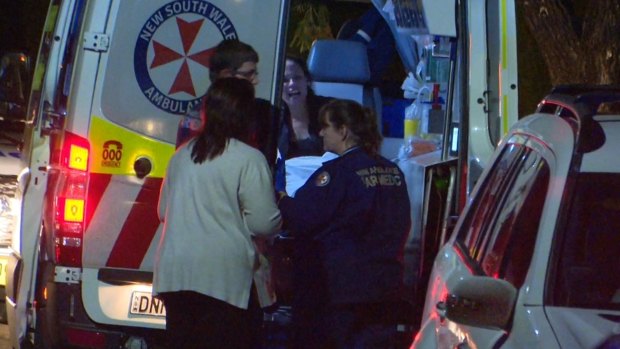 A woman is helped into the back of an ambulance.