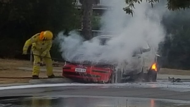 Firefighters extinguish the burning car.