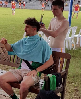 Tony Liberatore gets a haircut on the sidelines during a match with the Vietnam Swans.