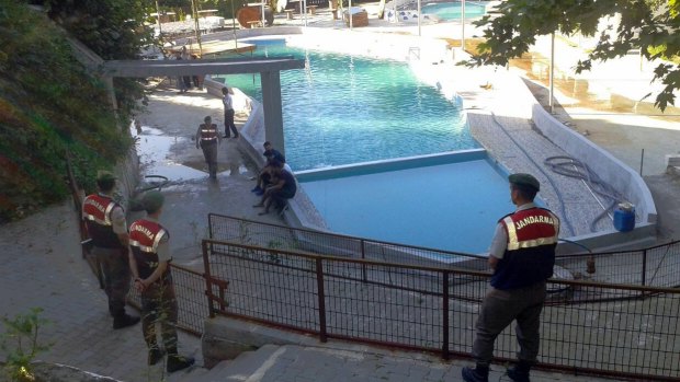 Paramilitary police officers investigate after five people were caught up in an electrical current in the pool.