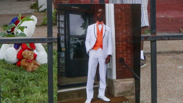 A photo of Mansur Ball-Bey stands in front of the steps where police shot him dead in St Louis.