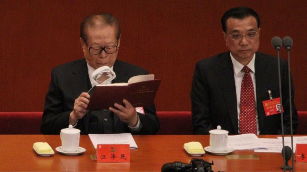 Former party general secretary Jiang Zemin reads during the meeting.