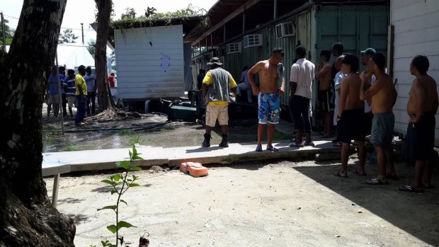 Papua New Guinean authorities oversee the emptying of garbage bins that have been used to collect rainwater. 