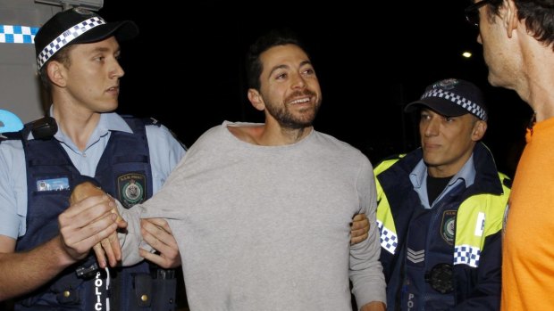 James Mathison is led away by police after trying to scale one of the Moreton Bay Fig trees on Anzac Parade, Moore Park, at a protest before they are cut down tonight in Sydney.