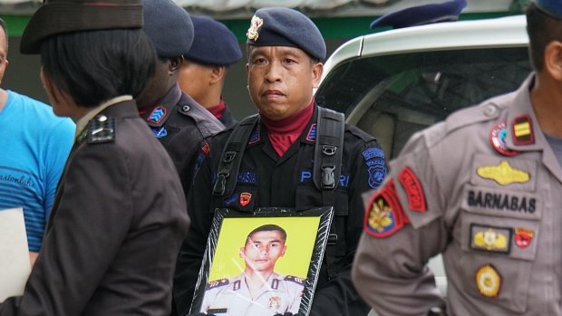 An officer holding Brigadier Firman's photo at his funeral.