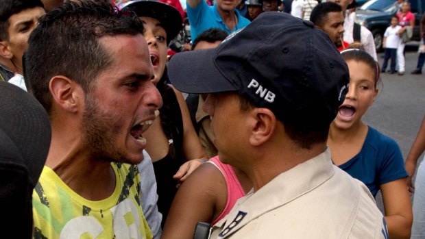 A man who was waiting in line at a grocery store argues with a police officer  in Caracas.