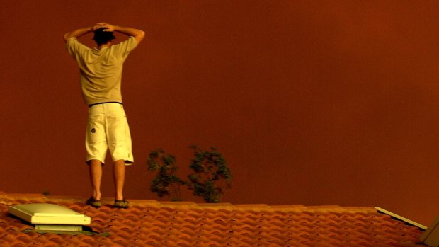 A residents watches the approaching red smoke from fires at Tharwa in 2003.