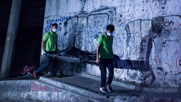 Mortuary workers carry the body of a summary execution victim on a stretcher in Manila. 