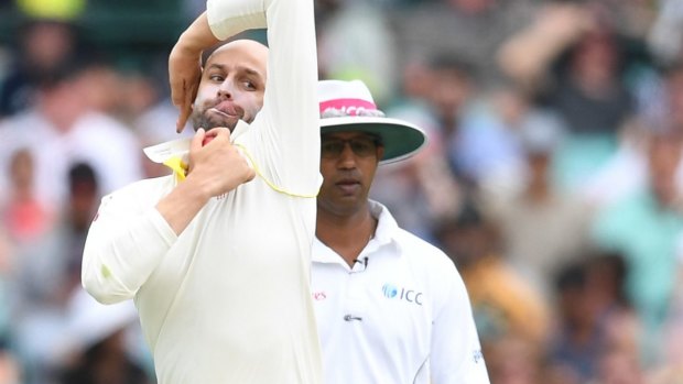 Contraband? Nathan Lyon bowls in front of umpire Kumar Dharmasena who is sporting an unauthorised pink band on his hat during the first session on day one.