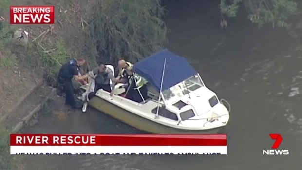 A paramedic helps a man to the riverbank after he is plucked from the Yarra. 