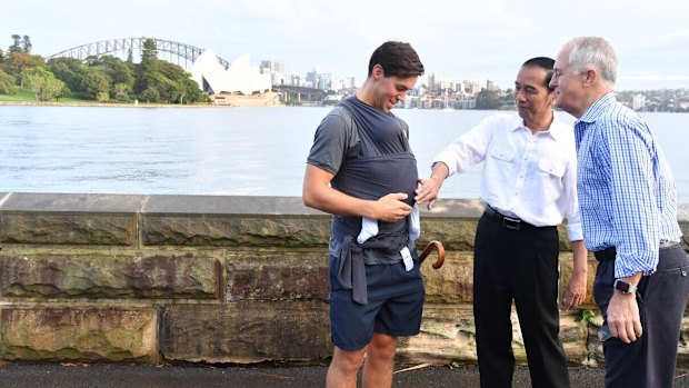 President Joko Widodo and Prime Minister Malcolm Turnbull talk to a father carrying his eight-week-old baby.