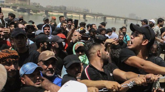 Protesters try to remove concrete barriers and cross the bridge towards the Green Zone area in Baghdad, Iraq, on Saturday, July 30.