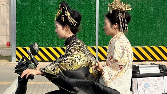 Due giovani donne in costumi tradizionali cinesi su uno scooter elettrico nel quartiere Dongcheng di Pechino est.