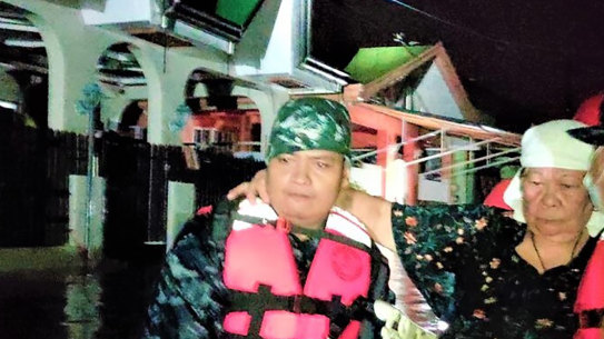 Rescuers carry a woman following the sudden rise in floodwaters as Typhoon Goni hit Batangas province, south of Manila.