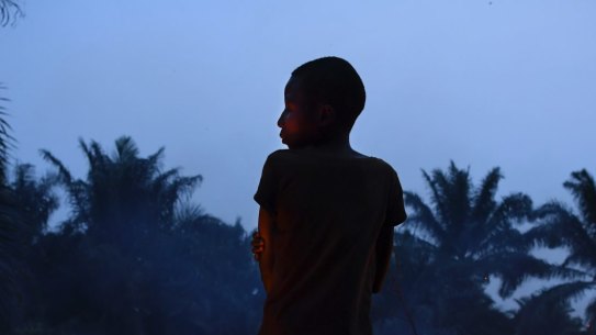 Former child soldier 'Wilson,' 15 years old watches over a small fire in his village in Kasai Central.