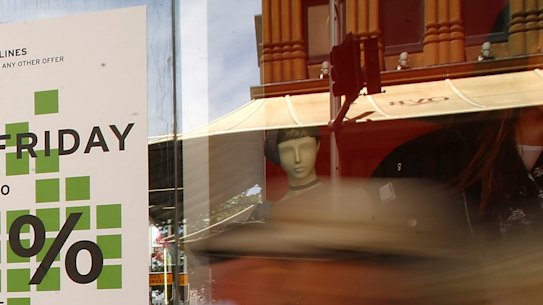  Pedestrians walk past in front of a Black Friday sale advertisement in Sydney, Australia. 