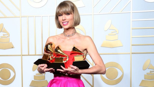 Taylor Swift cradles her three Grammys, including the biggest award - album of the year. 