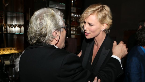 George Miller speaking with Charlize Theron at the pre Oscar party.