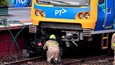 An emergency worker inspects the crushed car at Surrey Hills station.