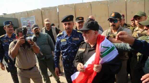 Iraq's Prime Minister Haider al-Abadi holds a national flag upon his arrival in Mosul on Sunday to mark the defeat of Islamic State in the city.