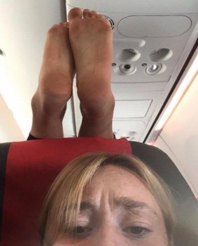 A plane passenger photographed a pair of dirty feet on her headrest, dangling just inches above her.