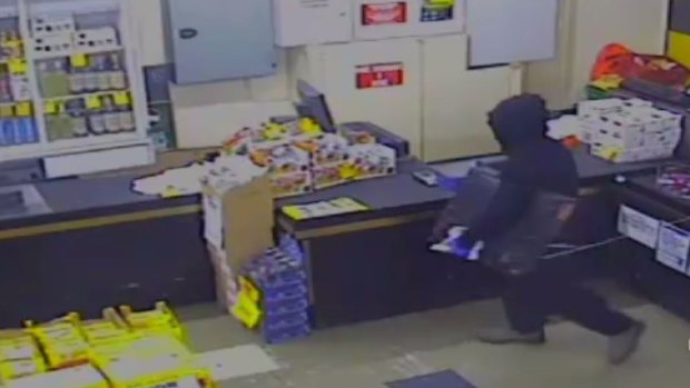 The burglar stealing a till machine from a Franston store.