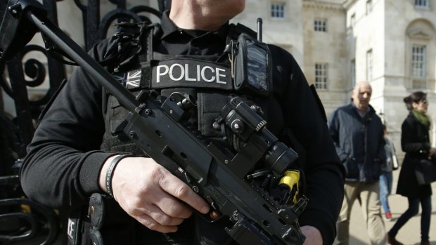 An armed British policeman stands on duty in central London.