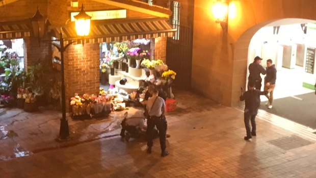 Police stand over a man at Central Station in Sydney following the shooting.