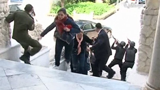 A still image taken from video shows tourists running for cover as armed men stand guard at Tunisia's national museum.