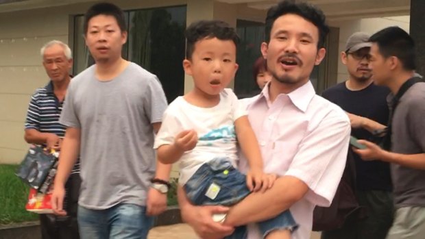 Chinese labour activists Li Zhao and Hua Haifeng (with his son) leave a police station after being released in Ganzhou following their arrest in relation to their investigations into factories used by Ivanka Trump's brand.