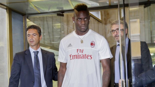 Back in Milan: Mario Balotelli wears an AC Milan jersey as he walks outside a clinic after undergoing medical checks in Milan.